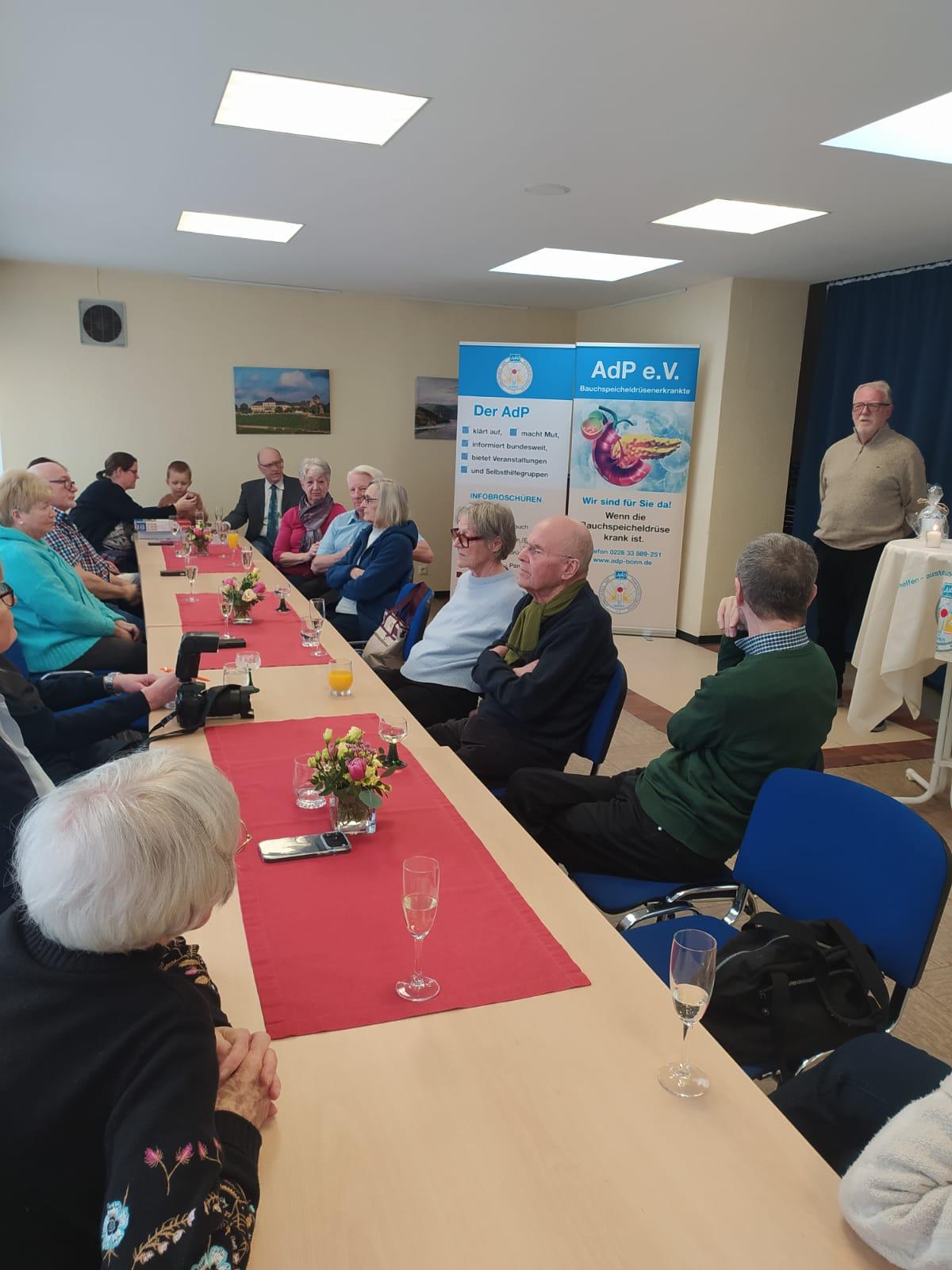 Die Veranstaltungsteilnehmer sitzen an einem langen Tisch